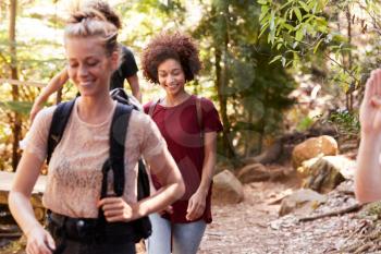 Millennial girlfriends walking together during a hike in a forest, close up