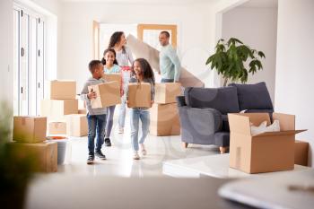 Smiling Family Carrying Boxes Into New Home On Moving Day