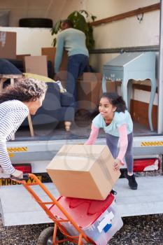 Family Unloading Furniture From Removal Truck Into New Home