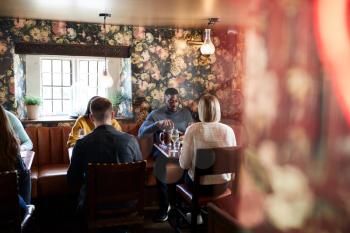 Group Of People Eating In Restaurant Of Busy Traditional English Pub