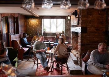 Couple Meeting For Lunchtime Drinks In Traditional English Pub