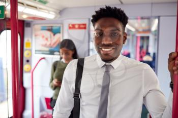 Portrait Of Smiling Businessman Standing In Train Commuting To Work