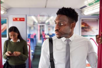 Businessman Standing In Train Commuting To Work