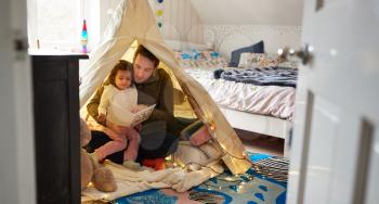 Single Father Reading With Daughter In Den In Bedroom At Home