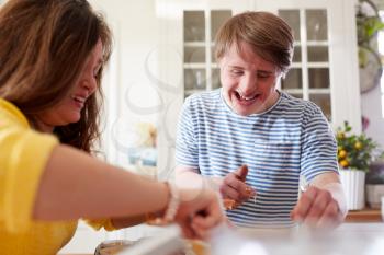 Young Downs Syndrome Couple Baking Cupcakes In Kitchen At Home