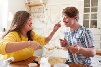 Young Downs Syndrome Couple Having Fun Baking Cupcakes In Kitchen At Home