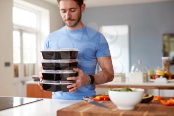 Man Preparing Batch Of Healthy Meals At Home In Kitchen