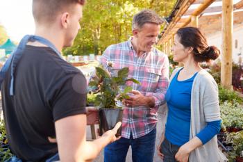 Mature Couple Buying Plants From Male Sales Assistant In Garden Center