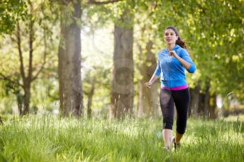 Young Woman Exercising Running Through Countryside Field