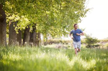 Man Exercising Running Through Countryside Field