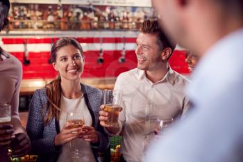 Male And Female Friends Meeting For Drinks And Socializing In Bar After Work