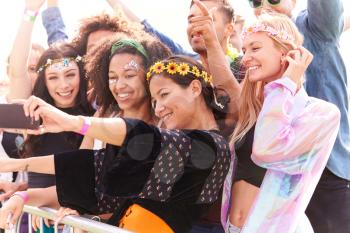 Young Friends In Audience Behind Barrier At Outdoor Music Festival Posing For Selfie