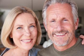 Portrait Of Smiling Senior Couple Standing At Home In Kitchen Together