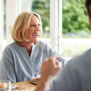 Family With Senior Mother And Adult Son Eating Brunch Around Table At Home Together