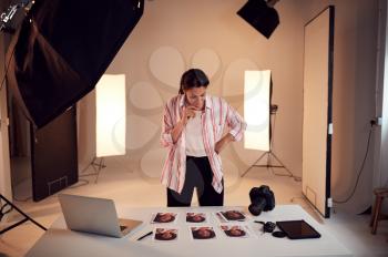 Female Photographer Editing Images From Photo Shoot In Studio