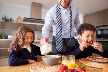 Businessman Father In Kitchen Helping Children With Breakfast Before Going To School