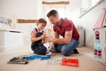 Father And Daughter In Bedroom Building Robot Kit Together