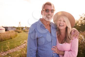 Portrait Of Loving Mature Couple In Countryside Hugging Against Flaring Sun