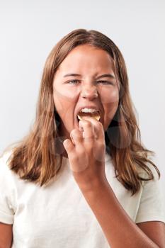 Studio Portrait Of Teenage Girl Eating Unhealthy Snack Of Crisps Against White Background