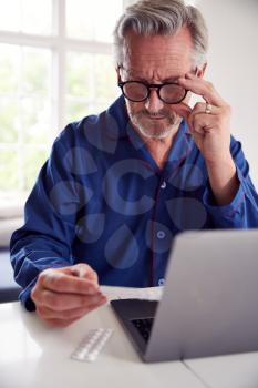 Mature Man At Home Looking Up Information About Medication Online Using Laptop