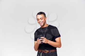 Studio Shot Of Causally Dressed Young Man Using Mobile Phone