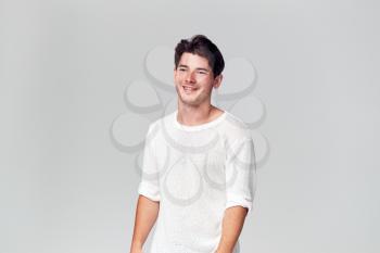 Studio Portrait Of Young Man Wearing White T Shirt Smiling Off Camera
