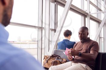 Male Passenger In Airport Departure Lounge Checking Travel Documents