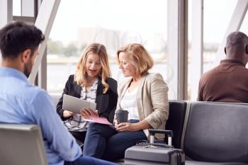 Businesswomen Sitting In Airport Departure Working On Laptop