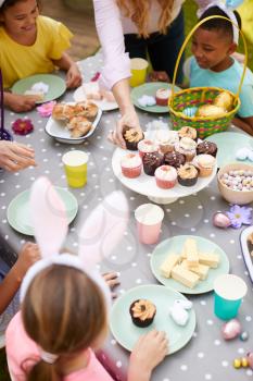 Mother With Children Wearing Bunny Ears Enjoying Outdoor Easter Party In Garden At Home