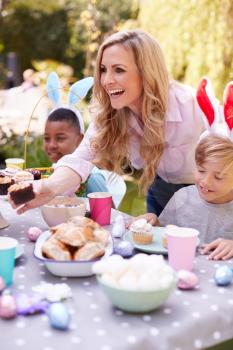Mother With Children Wearing Bunny Ears Enjoying Outdoor Easter Party In Garden At Home
