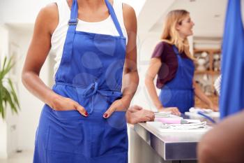 Close Up Of Woman With Hands In Apron Pocket Taking Part In Cookery Class In Kitchen
