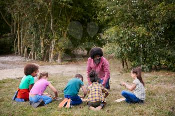 Team Leader Showing Group Of Children On Outdoor Camping Trip How To Make Fire