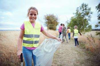 Portrait Of Girl With Adult Team Leaders At Outdoor Activity Camp Collecting Litter With Friends