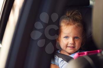 Portrait Of Young Girl Watching Digital Tablet In Back Seat On Car Journey