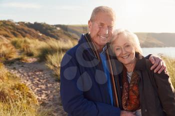 Portrait Of Loving Active Senior Couple Walking Through Sand Dunes  In Autumn Together