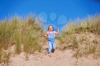Young Girl Having Fun On Beach Vacation Running Down Sand Dunes