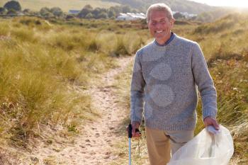 Portrait Of Senior Man Collecting Litter On Winter Beach Clean Up