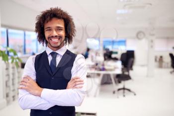 Portrait Of Confident Young Businessman Wearing Suit Standing In Modern Office
