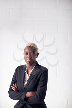 Portrait Of Determined Young Businesswoman Wearing Suit Standing Against White Studio Wall