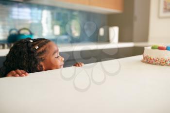 Girl Hiding Behind Kitchen Counter Takes Sneaky Look At Birthday Cake