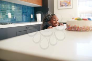 Girl Hiding Behind Kitchen Counter Takes Sneaky Look At Birthday Cake