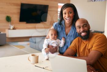 Portrait Of African American Family With Baby Daughter Using Laptop To Check Finances At Home