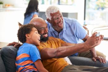 Multi-Generation Male African American Family On Sofa At Home Posing For Selfie On Mobile Phone