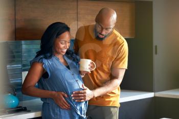 Loving African American Husband With Pregnant Wife At Home In Kitchen Together