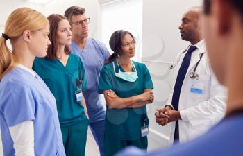 Multi-Cultural Medical Team Having Meeting In Hospital Corridor