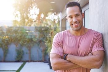 Portrait Of Smiling Hispanic Man In Garden At Home Against Flaring Sun