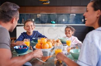 Hispanic Family Sitting Around Table Eating Breakfast Together