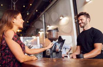 Female Customer Paying Barista At Coffee Shop Sales Desk