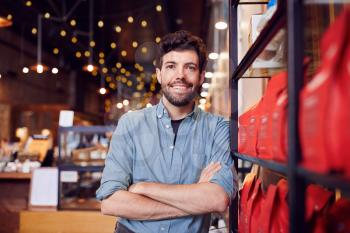 Portrait Of Male Coffee Shop Owner Standing By Counter