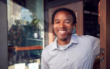 Portrait Of Male Owner Of Start Up Coffee Shop Or Restaurant Standing In Doorway